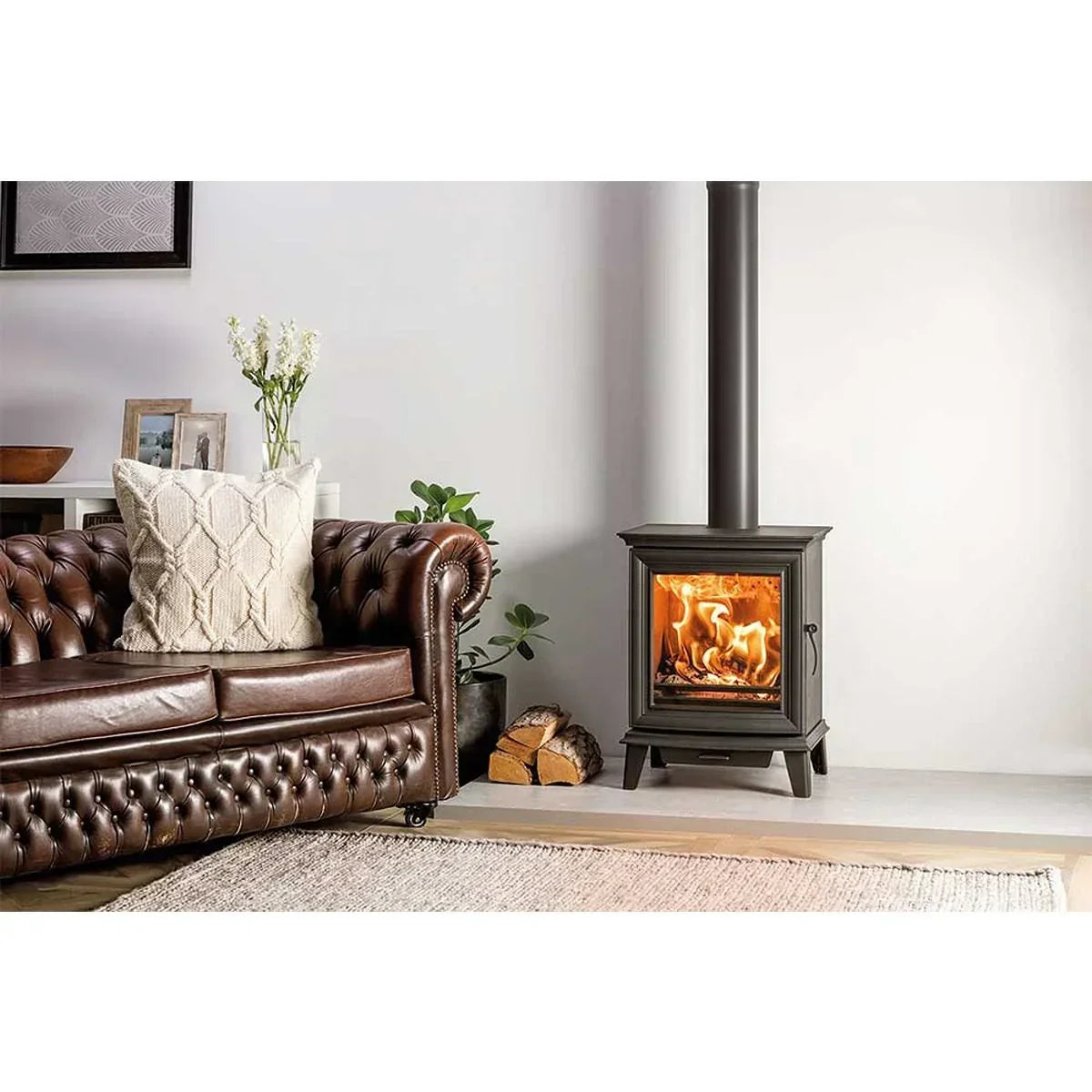 Leather Chesterfield sofa beside modern wood burning stove in cosy living room setting