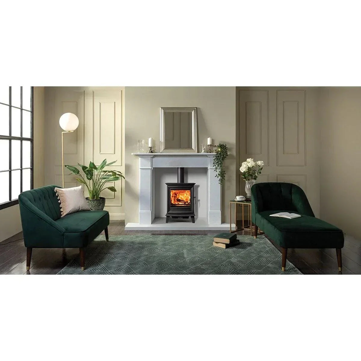 Living room with green velvet sofa and chaise, wood burning stove, and white fireplace
