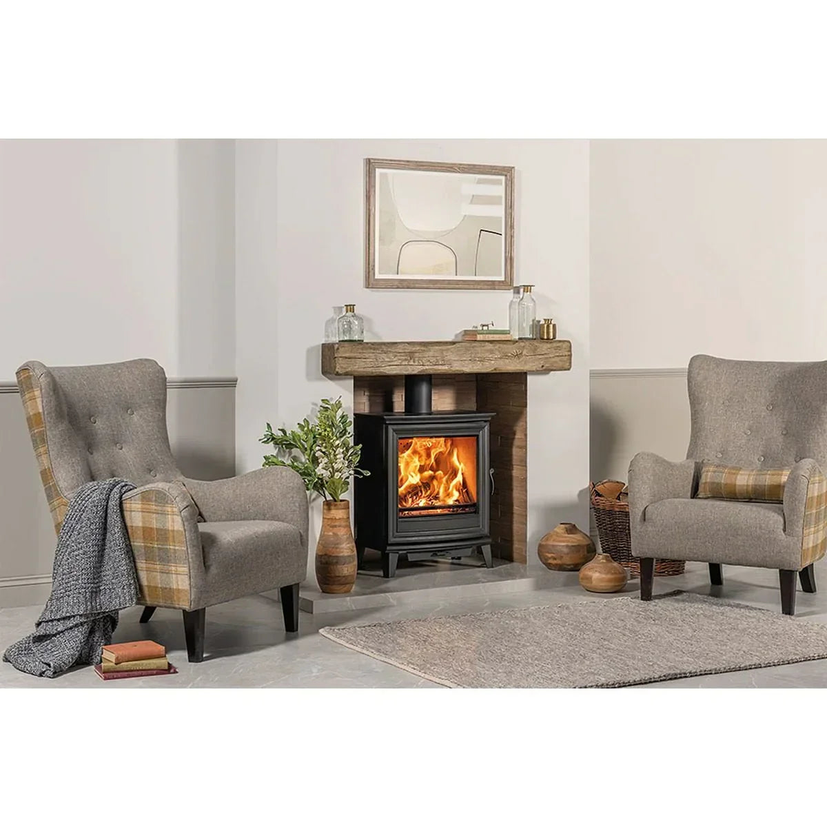 Grey fabric armchairs with plaid accents beside wood burning stove in modern living room