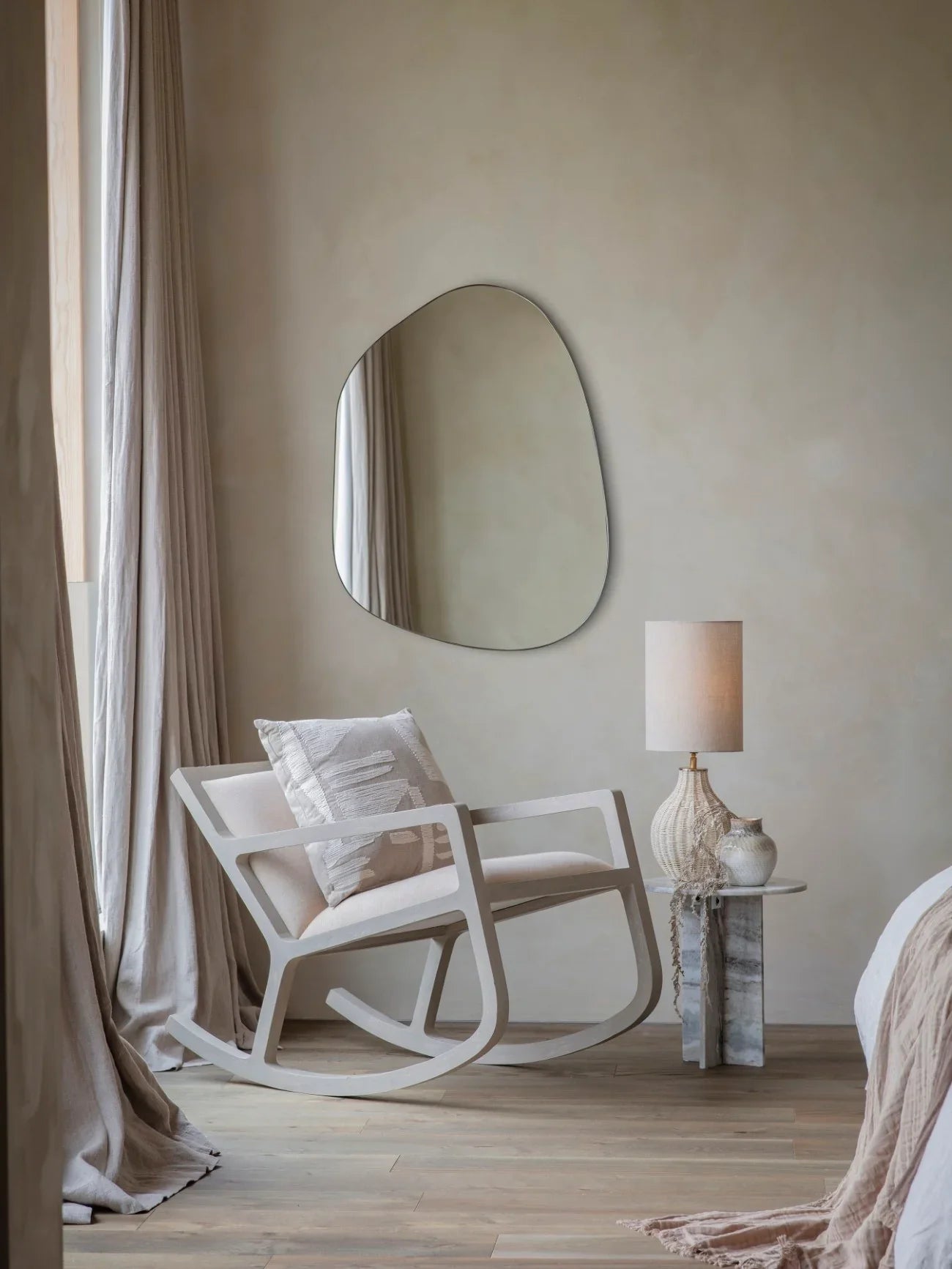 Beige rocking chair in cozy bedroom with textured pillow and soft drapes.
