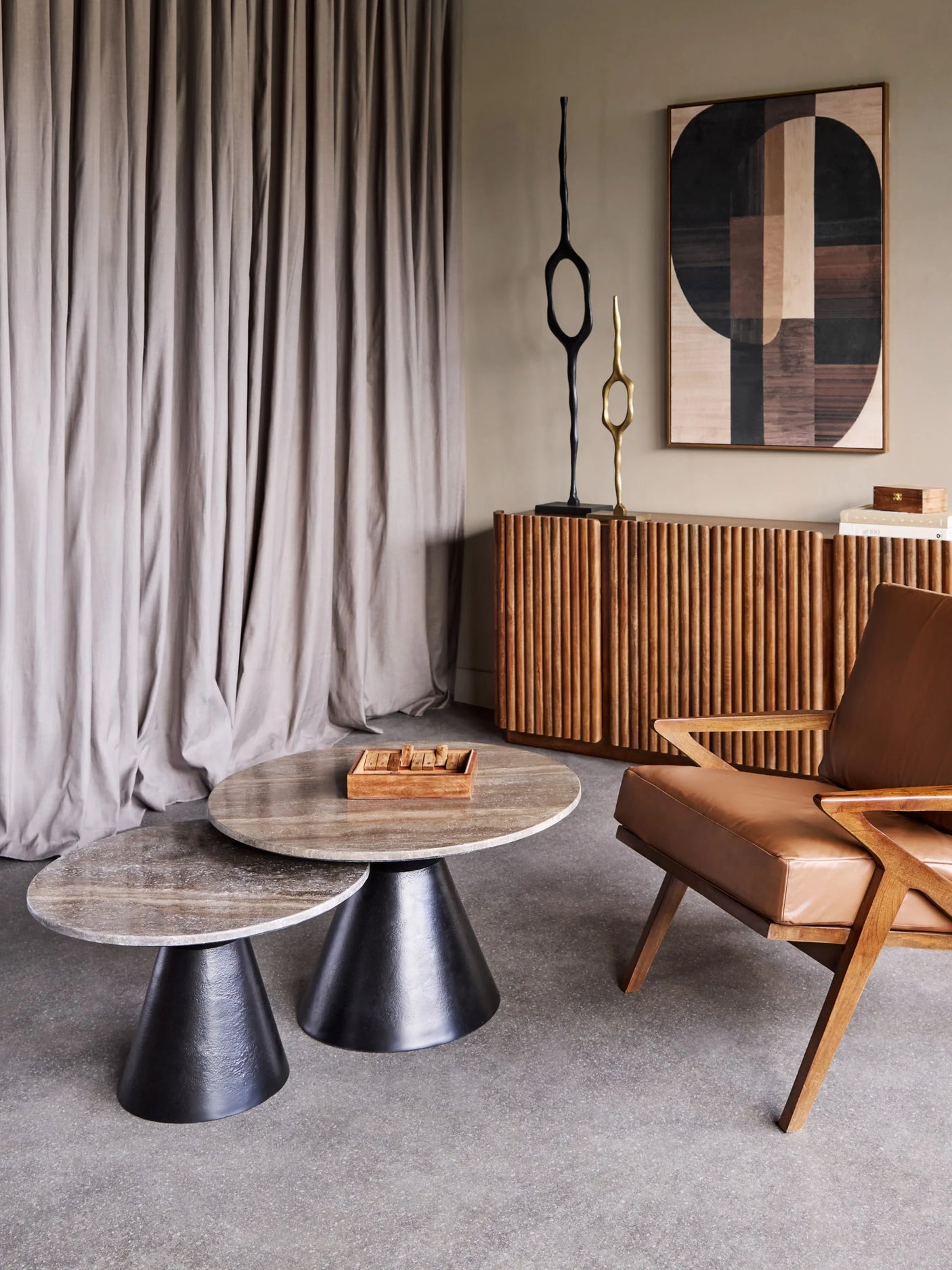 Round travertine coffee tables in modern living room with wooden chair and decor.