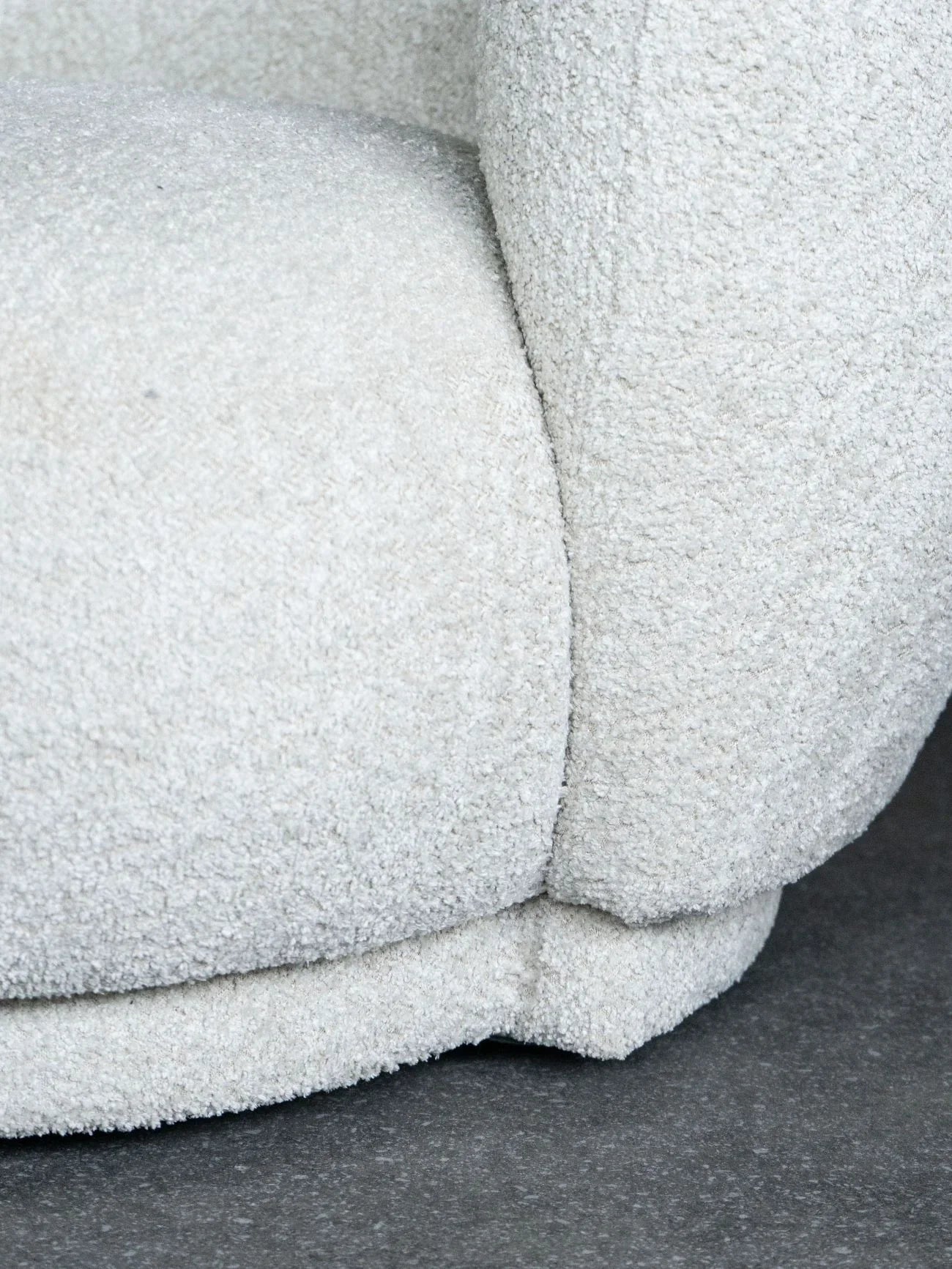 Cream sofa corner with textured fabric detail on a dark floor.