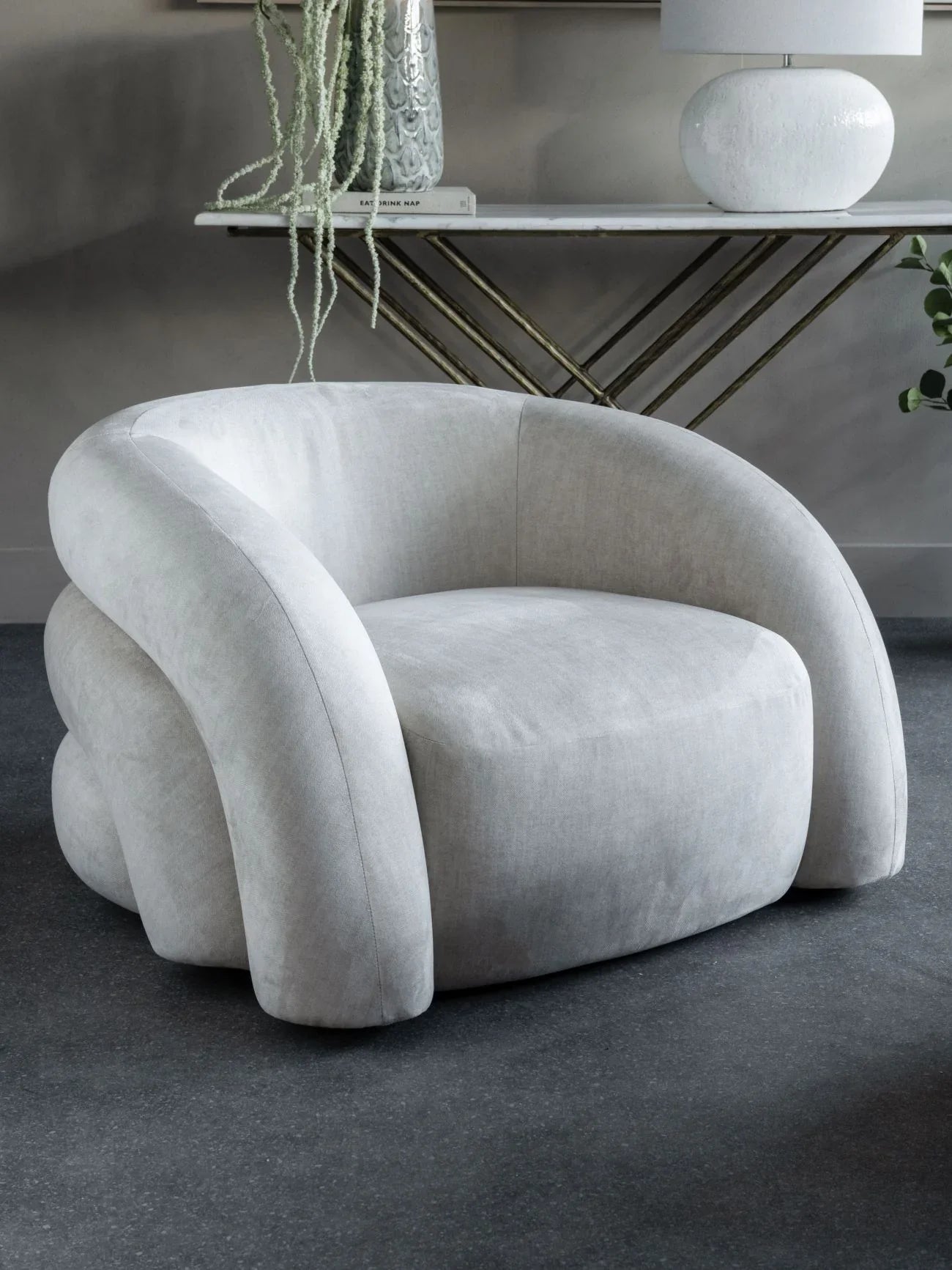 Cream upholstered chair in a modern room with a console table.