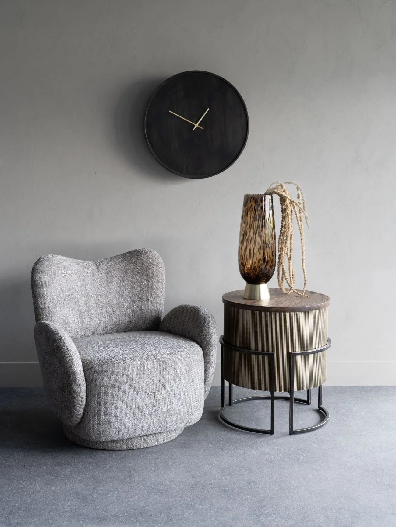 Neutral swivel chair in a modern room with a side table and wall clock.