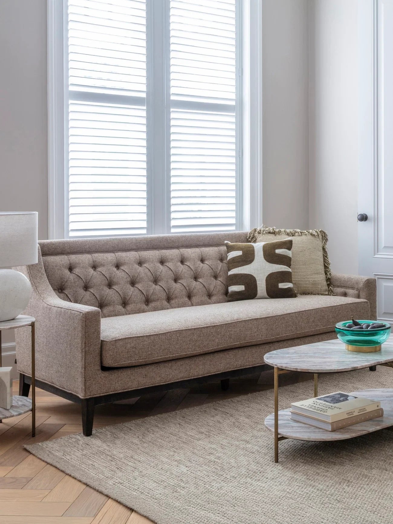Dark taupe sofa in a bright room with a patterned cushion and coffee table.
