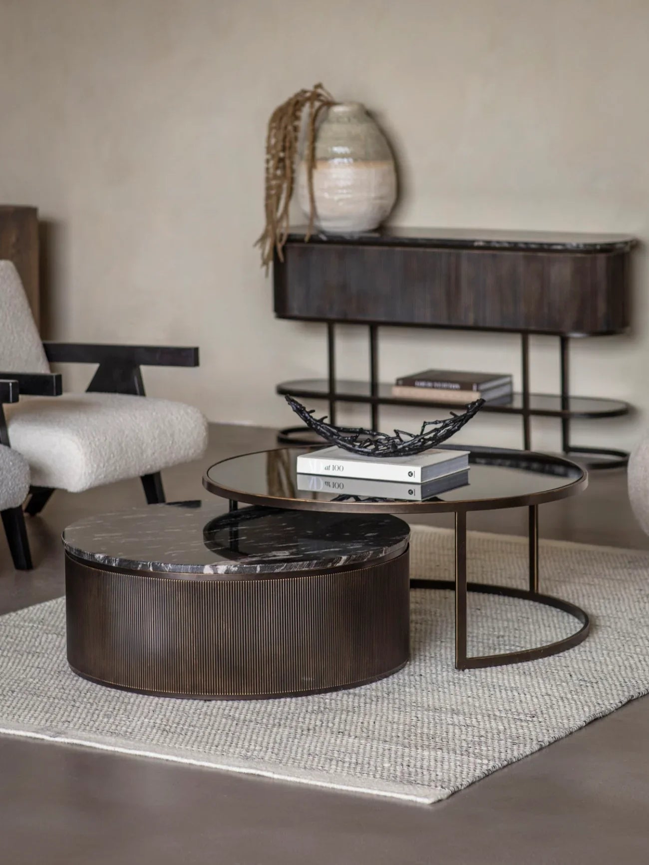 Black nesting coffee tables in a modern living room with a textured rug.