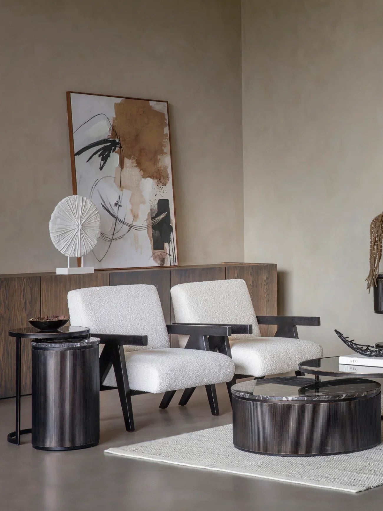 Black nesting tables in modern living room with white armchairs and abstract art.