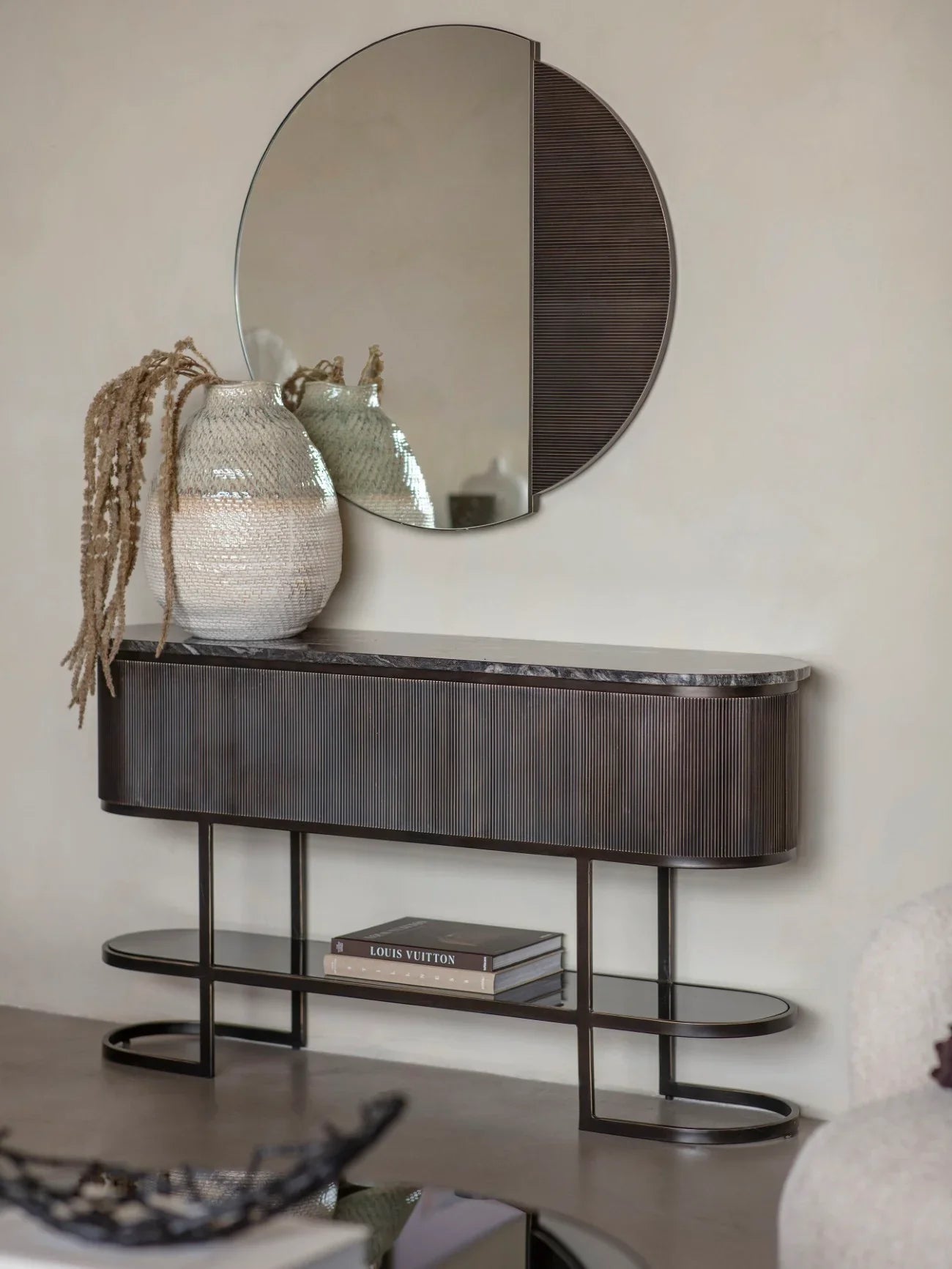 Black console table with decorative vases and books in a modern living room.