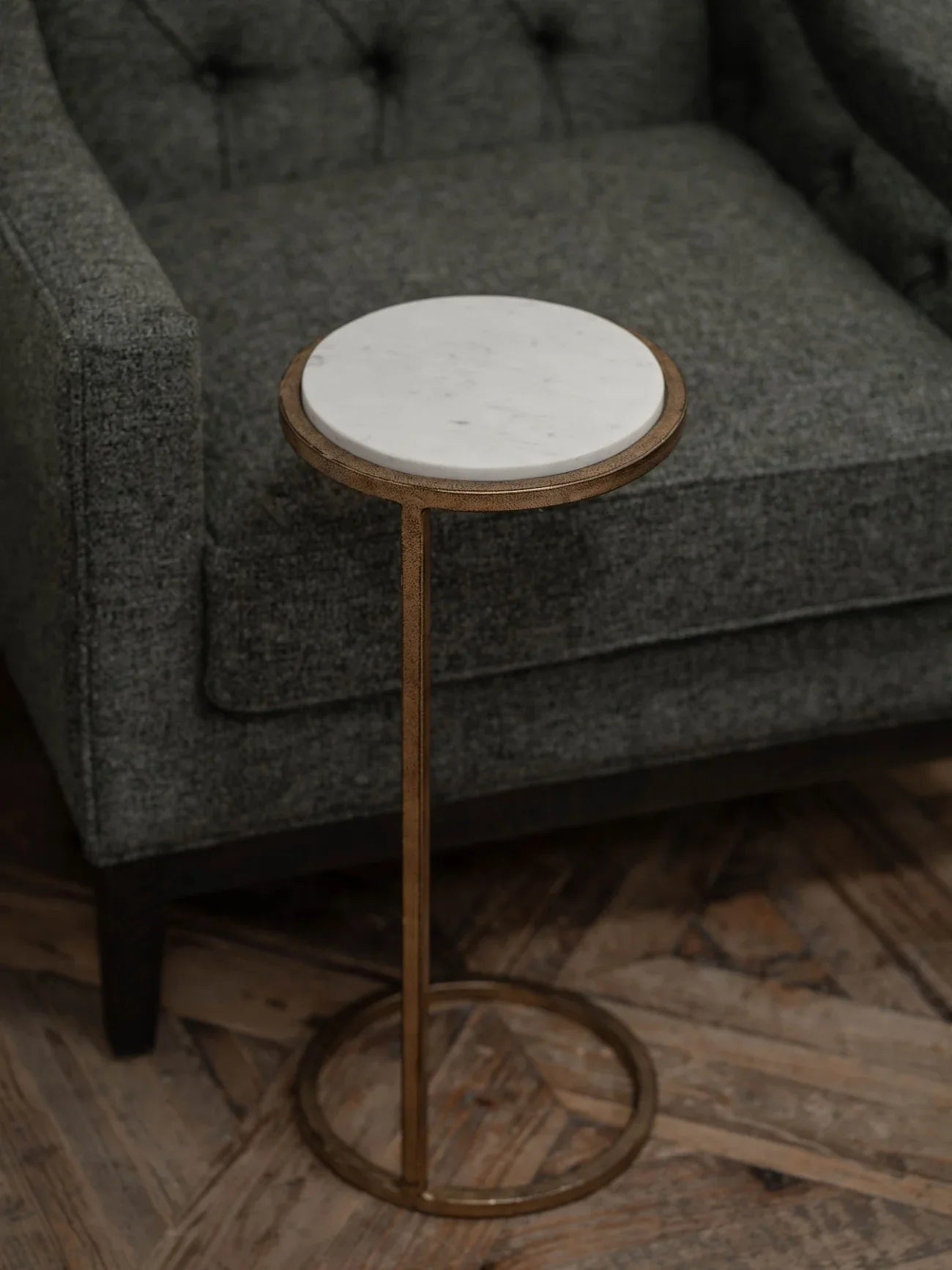 White marble-topped table beside a grey upholstered chair on wooden flooring.