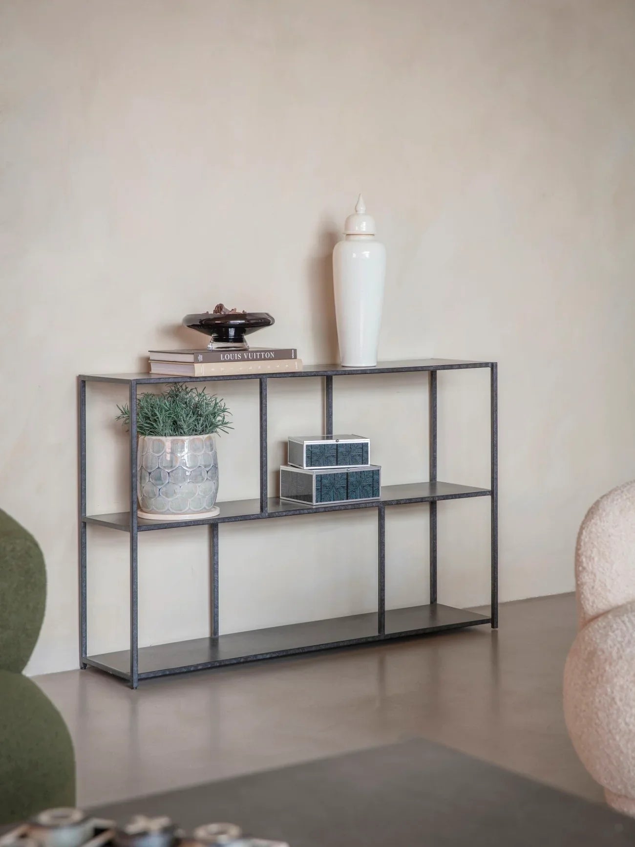 Mottled black console table with decor in a minimalist living room setting.