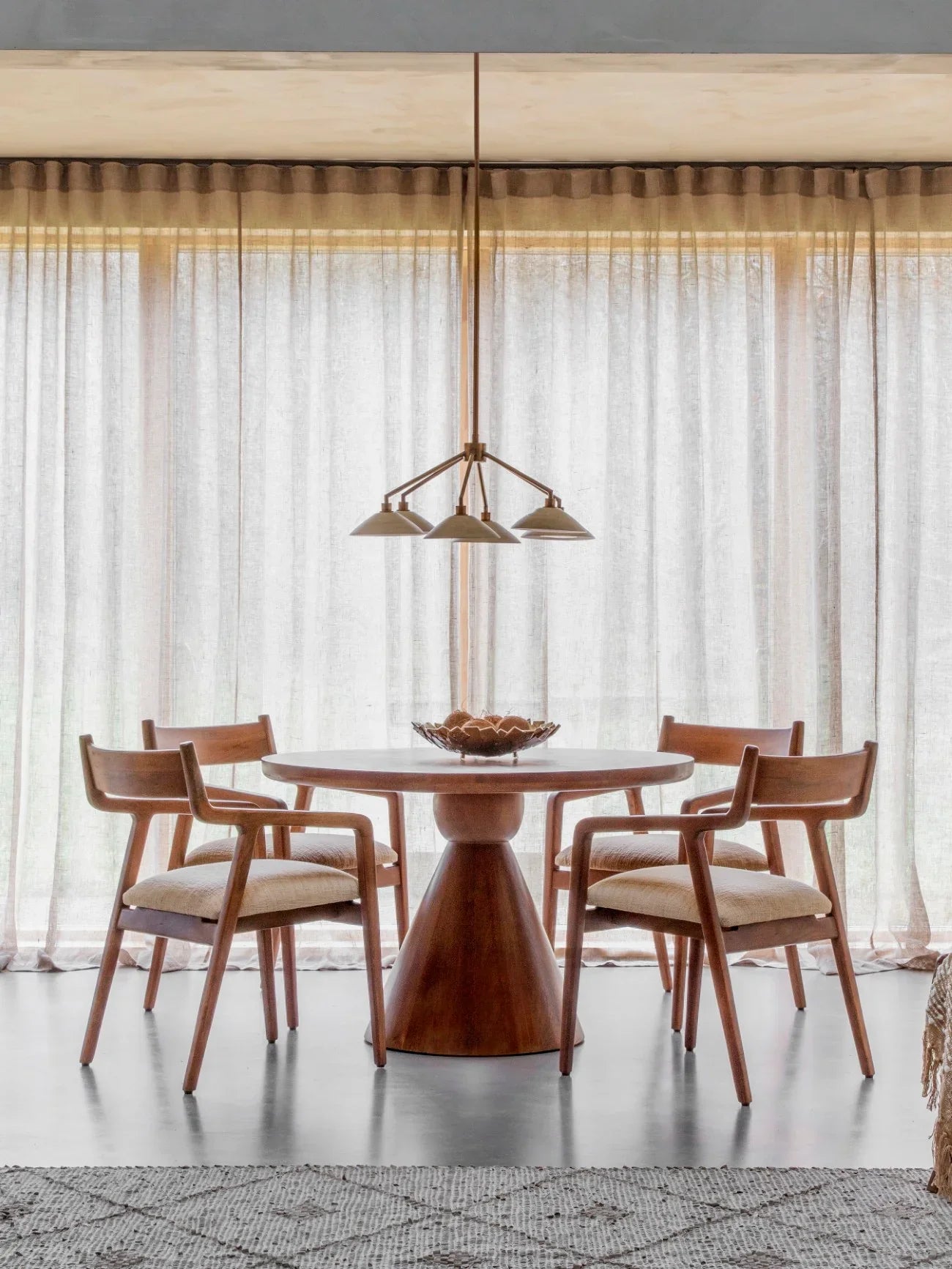Round wooden table with chairs in a bright dining room setting.
