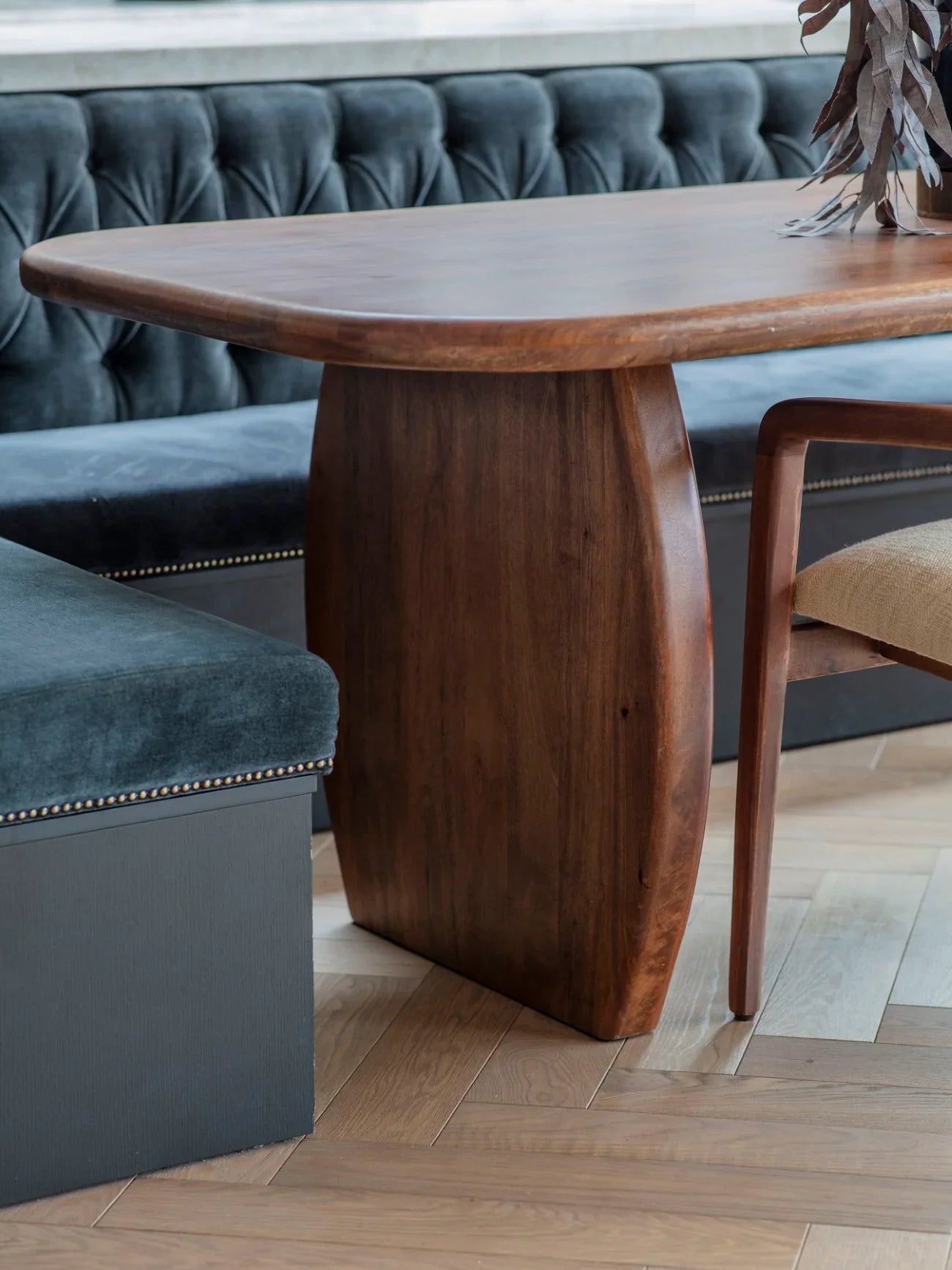 Smooth wooden dining table with curved edges in a cozy dining nook.
