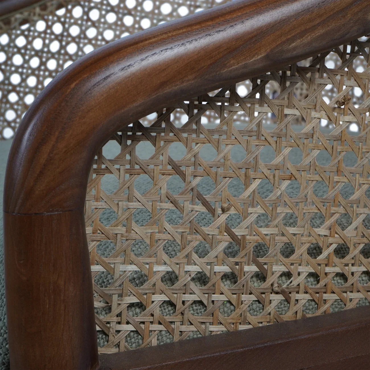Dark wood armchair with intricate cane backrest detail.