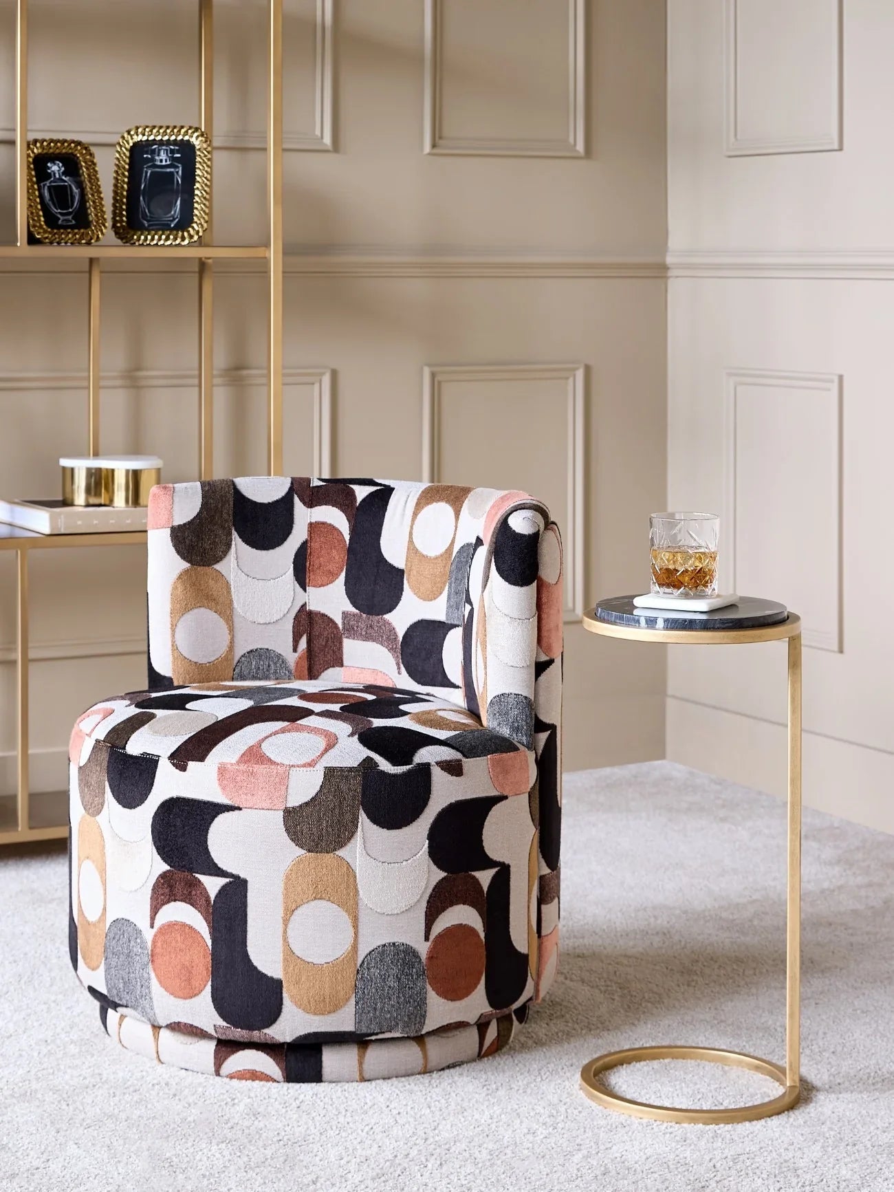 Patterned swivel chair in a cozy room with a gold side table and shelf.