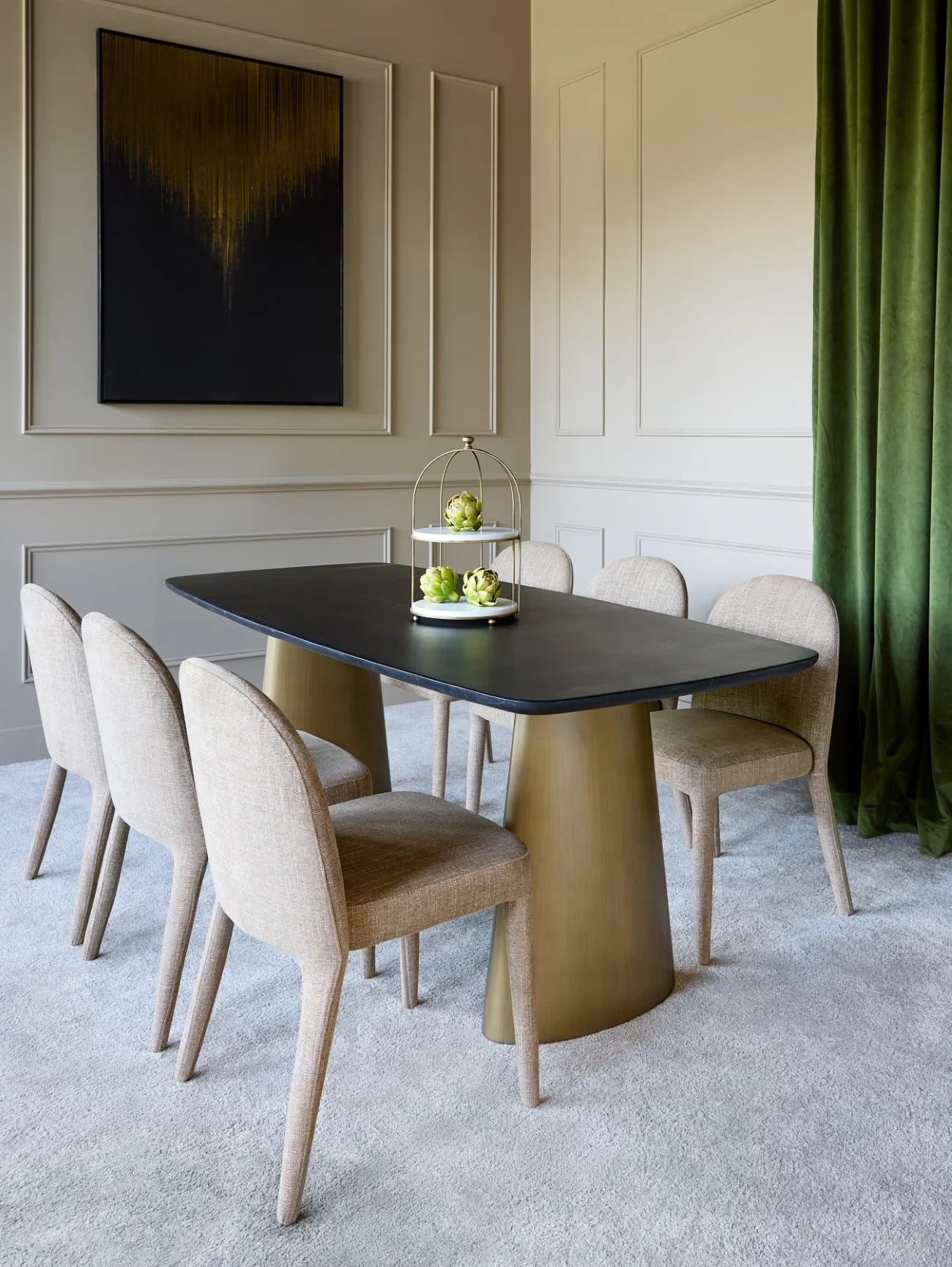 Black marble dining table with brass legs in elegant dining room setting.