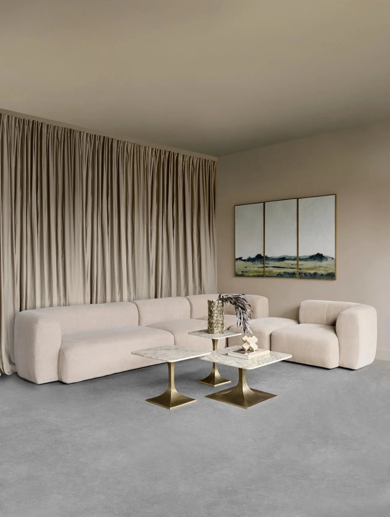 Beige sectional sofa in elegant living room with marble tables.