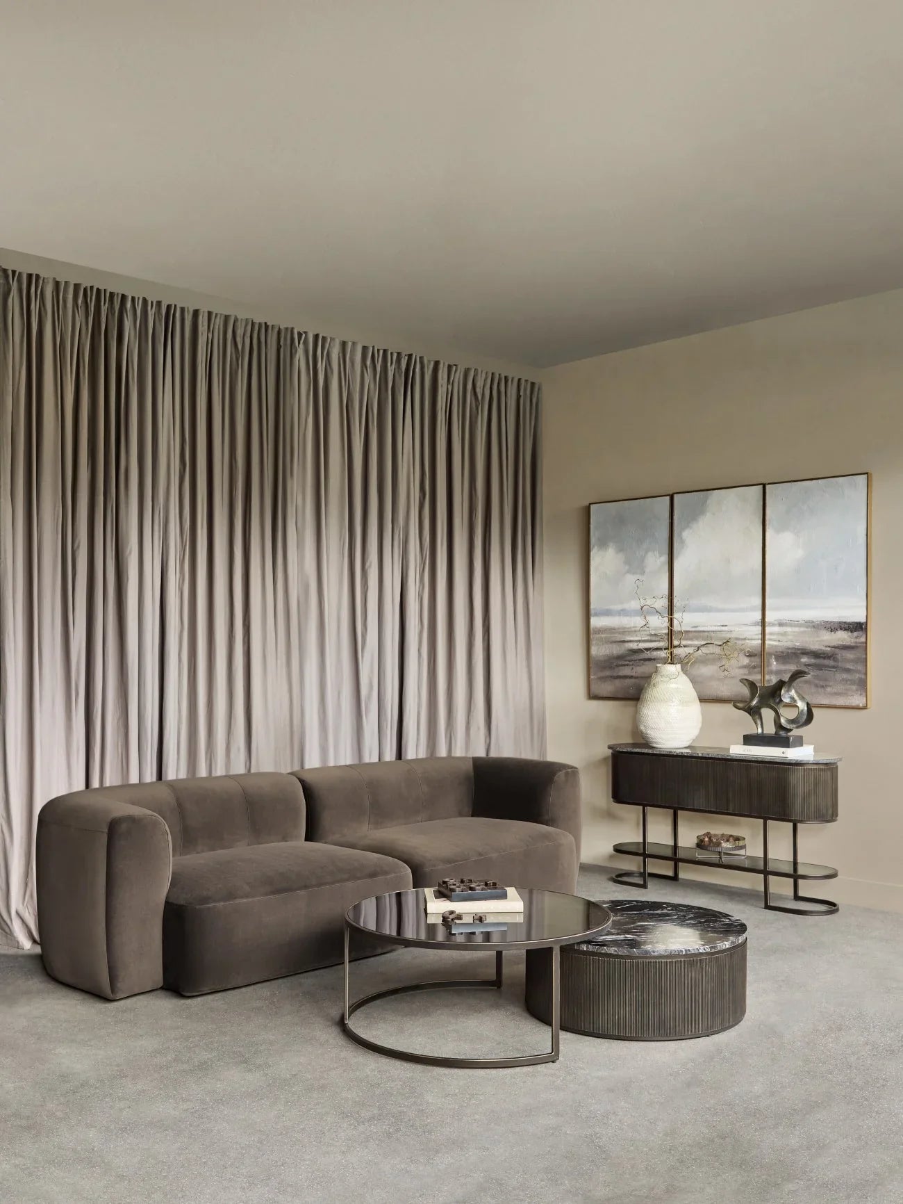 Brown velvet sofa in elegant living room with modern decor and soft drapes.