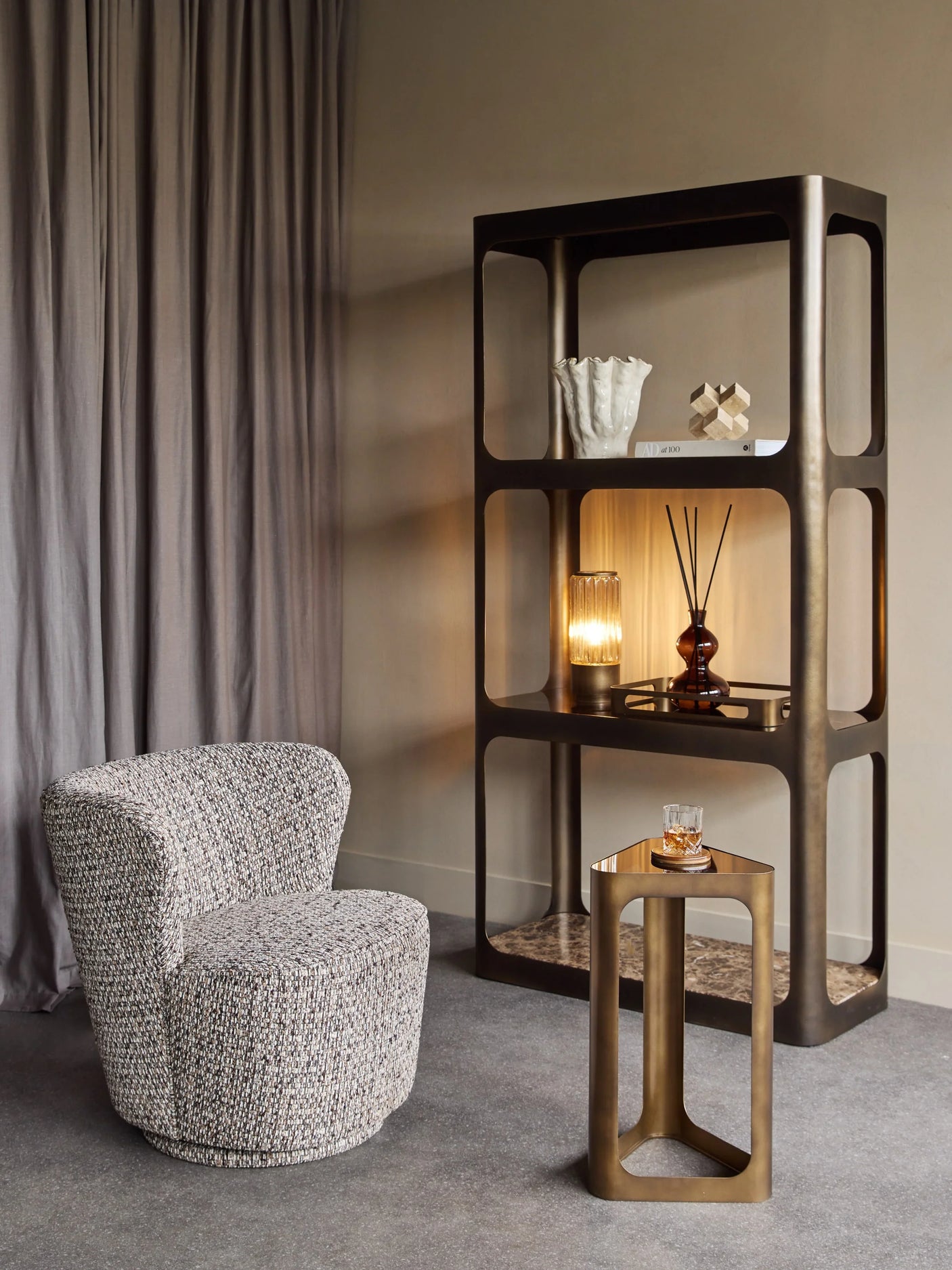 Cozy room with bronze shelving unit, textured chair, and marble accents.