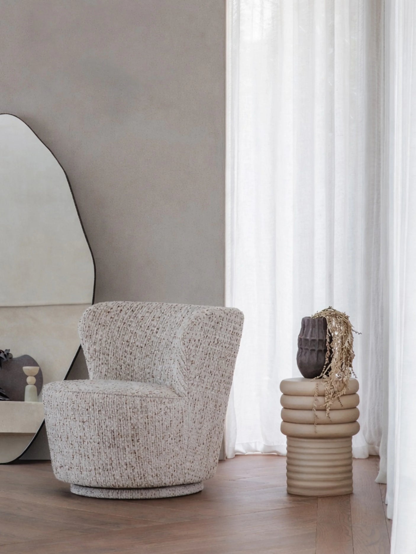 Beige ribbed side table with decorative vase in a modern living room.
