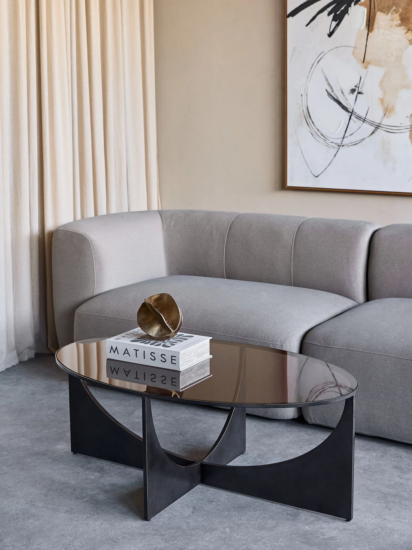 Black sculpted coffee table in modern living room with grey sofa and abstract art.