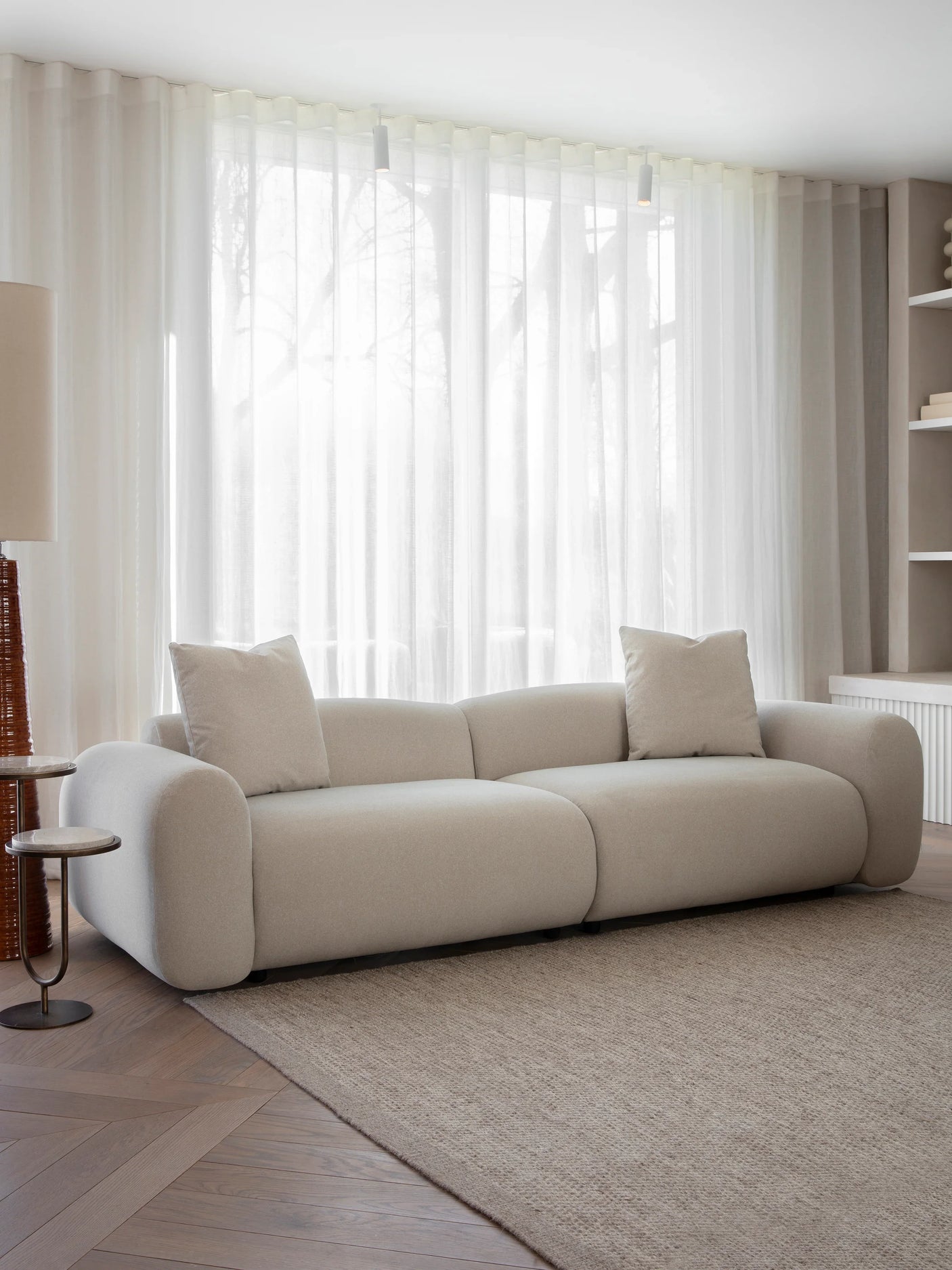 Warm stone velvet sofa in bright living room with sheer curtains