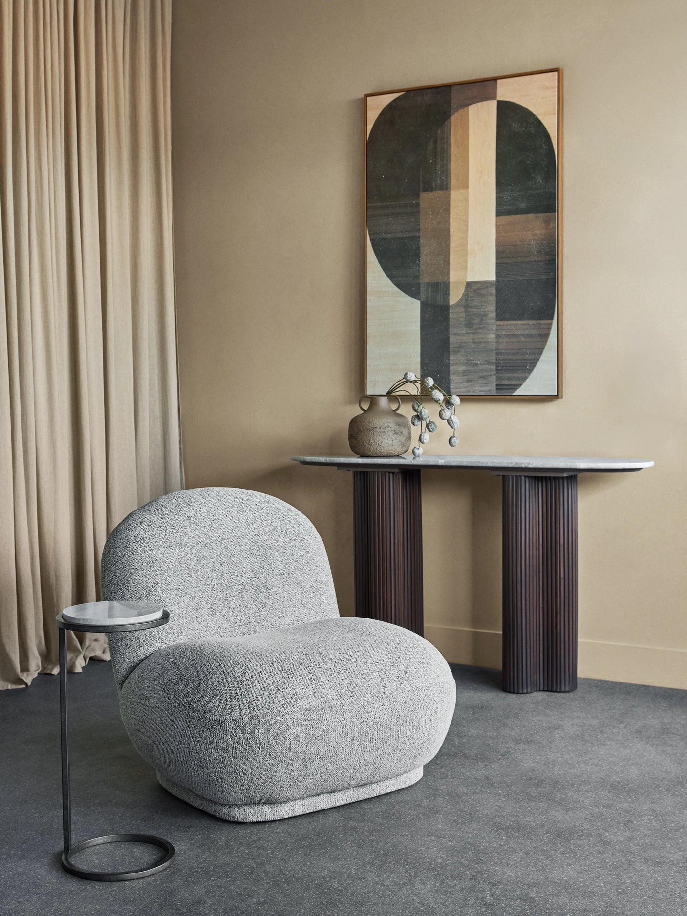 Grey textured chair in modern room with abstract art and console table.