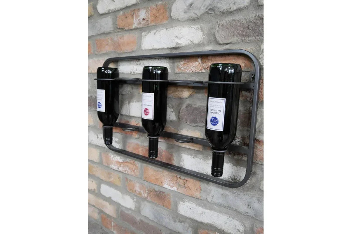 Wall mounted metal wine rack holding three bottles against exposed brick