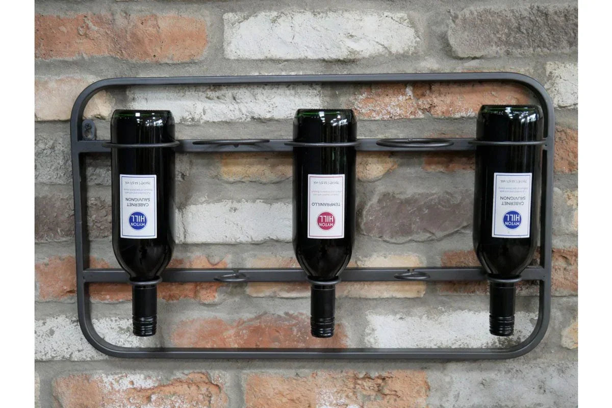 Wall-mounted metal wine rack holding three bottles against exposed brick wall
