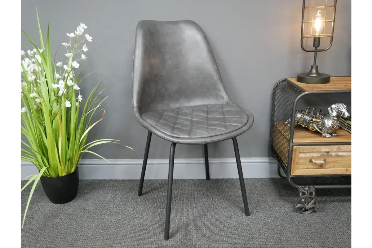 Grey dining chair with quilted seat and black metal legs in modern room setting