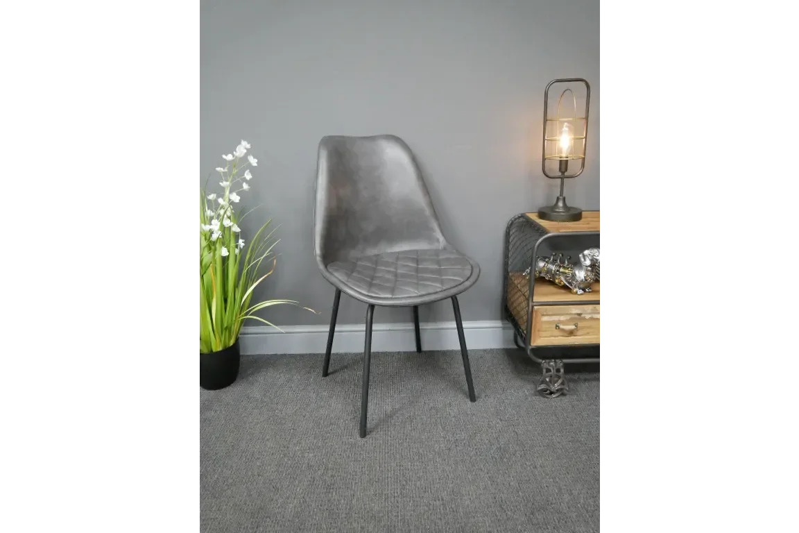 Grey faux leather dining chair with black metal legs against a grey wall, indoor setting