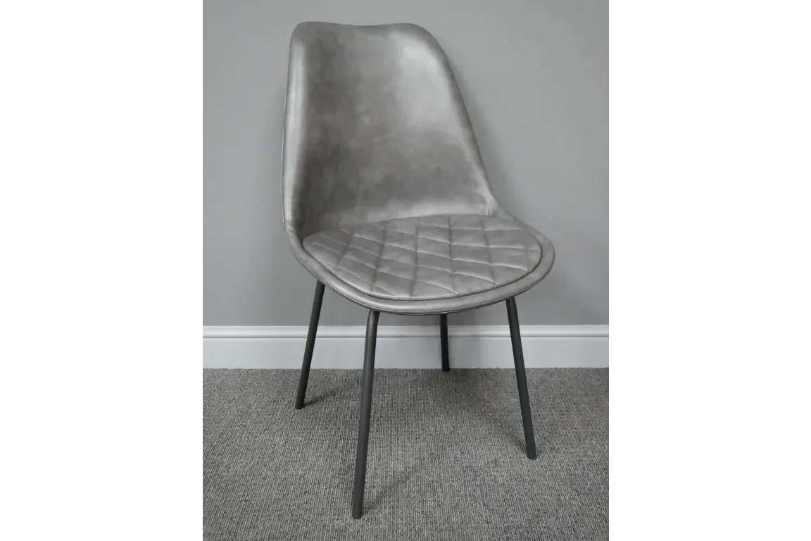 Grey faux leather dining chair with quilted seat and black metal legs on carpet