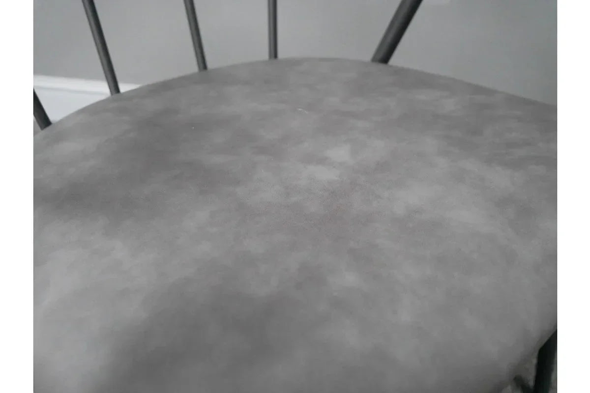 Close detail of grey upholstered dining chair seat with metal backrest