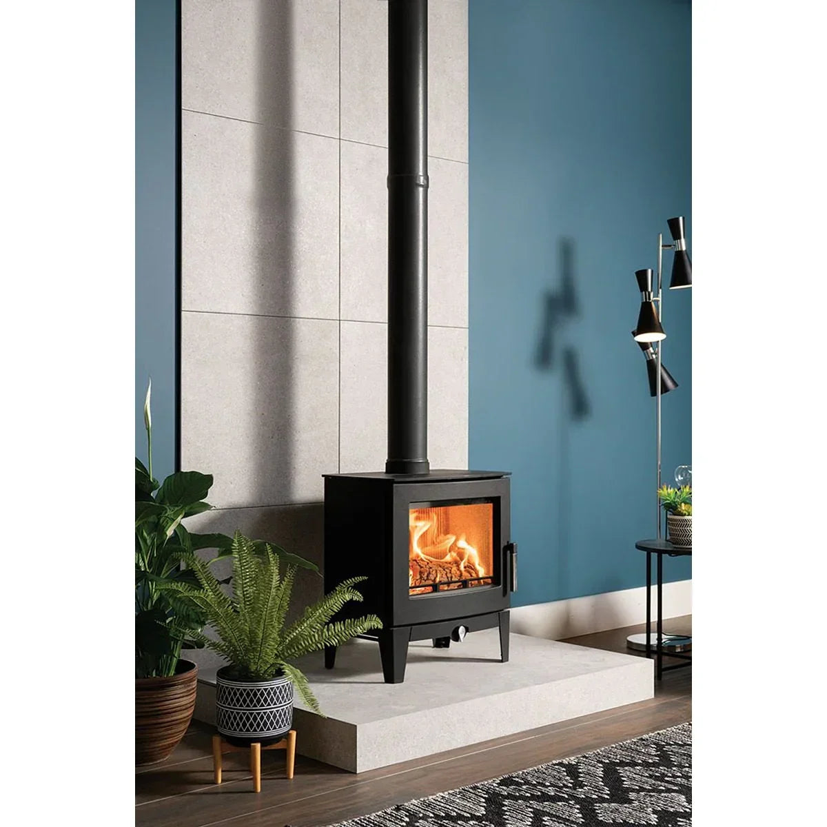 Black wood burning stove with visible flames on stone hearth, modern living room setting