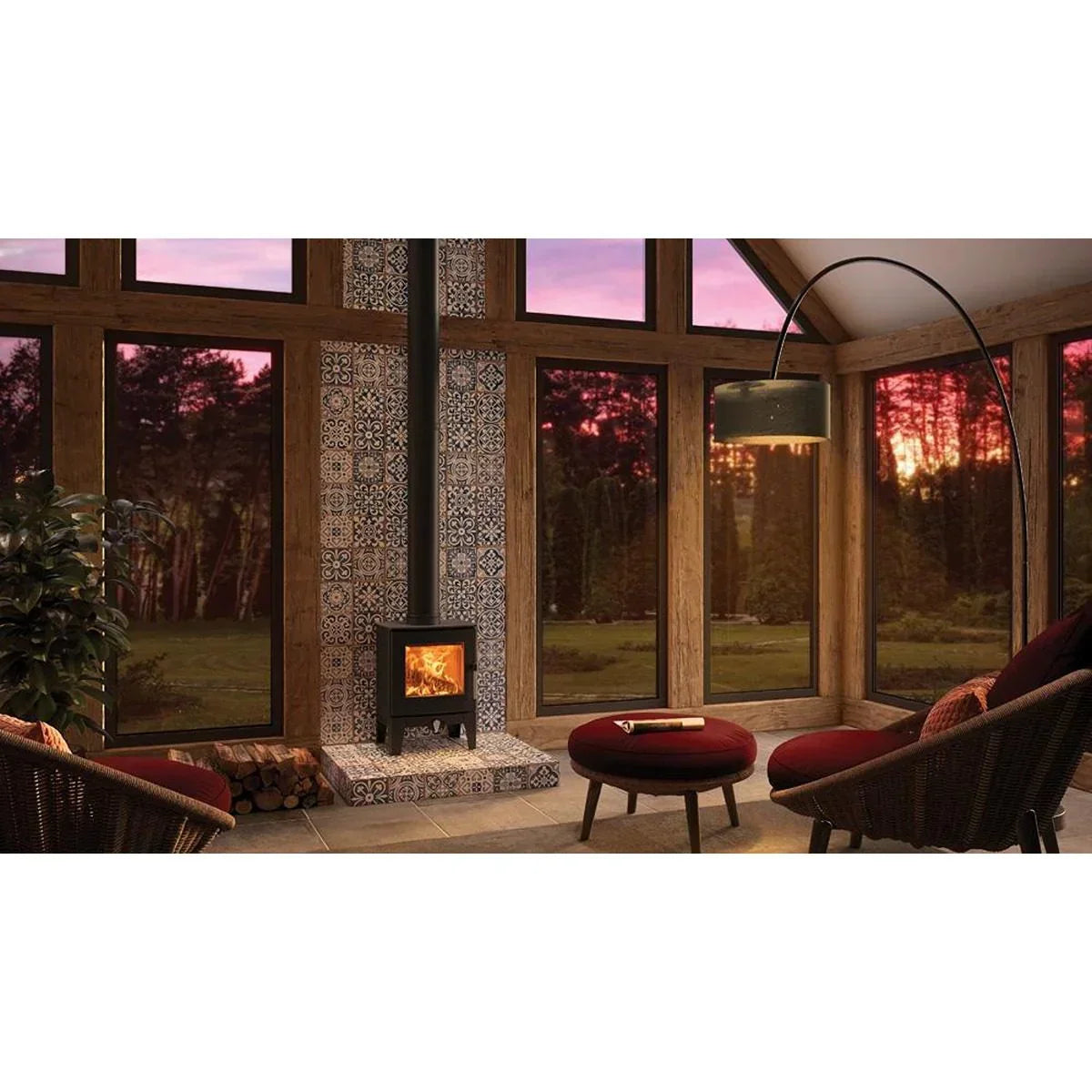 Modern wood burning stove with patterned tile backdrop in a sunroom with large windows