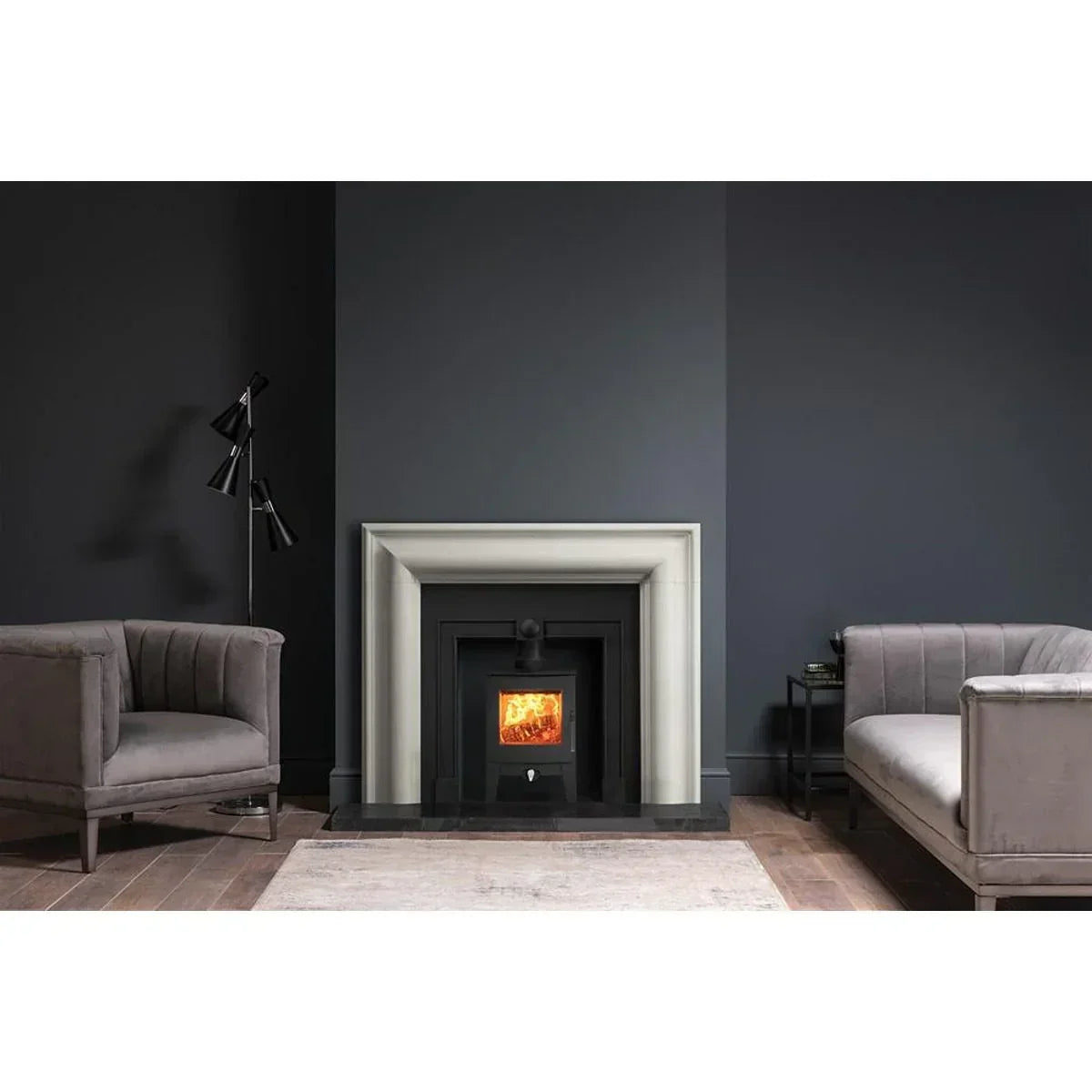 Modern grey fireplace suite with burning wood stove, flanked by two grey velvet sofas