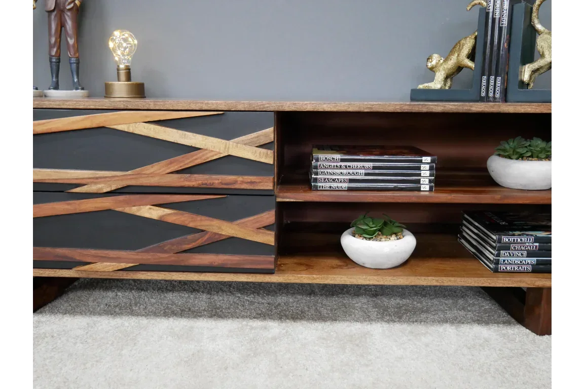 Modern wood TV unit with black drawer fronts, open shelves, books, and small succulents