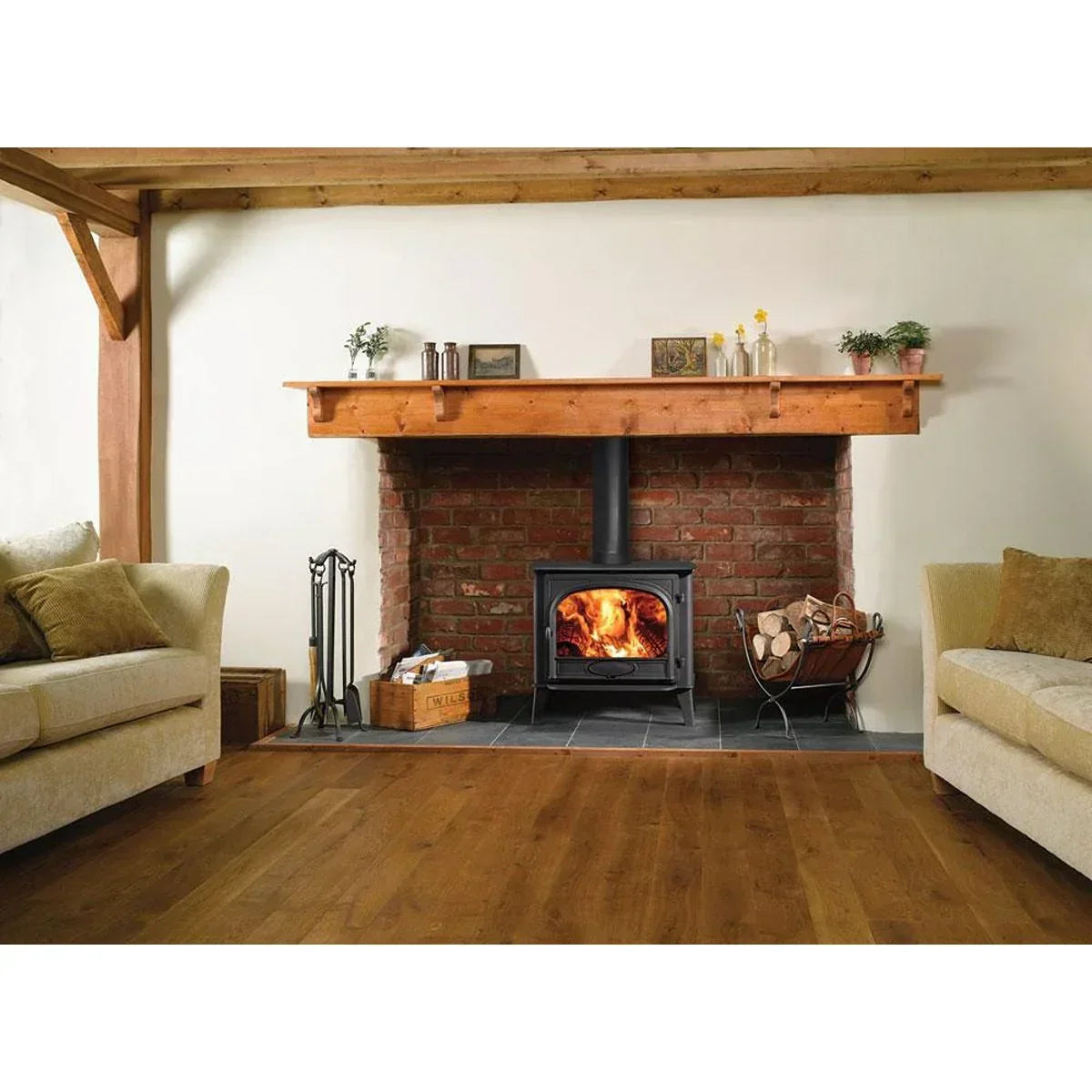 Wood burning stove with brick fireplace surround and mantel in living room setting
