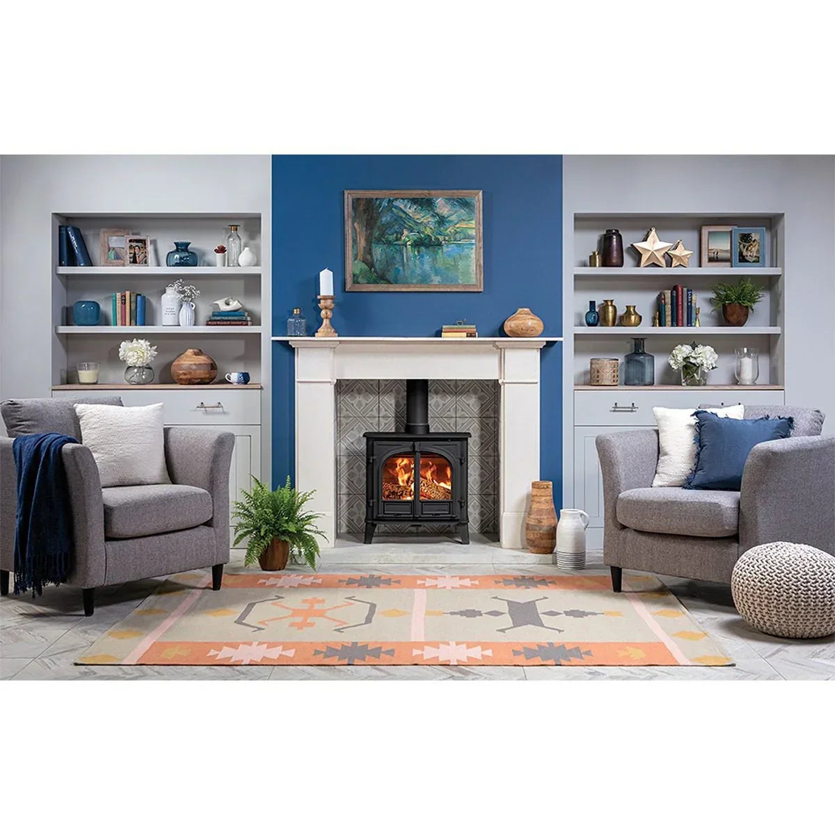Modern living room with grey fabric armchairs, patterned rug, wood stove and built-in shelves