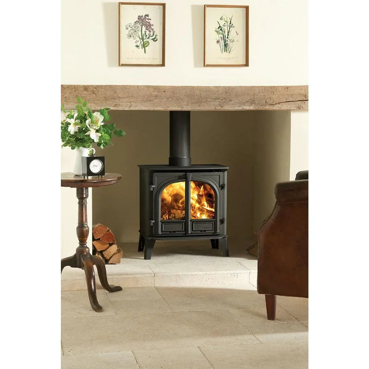 Black wood burning stove with glass doors in a rustic living room fireplace setting