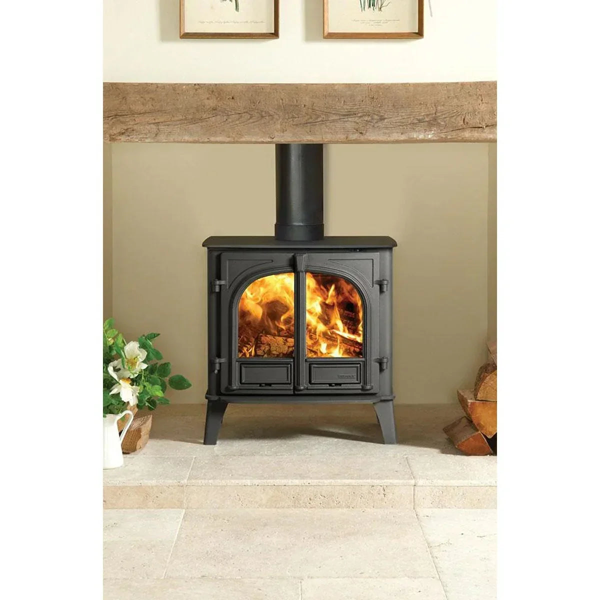 Black wood burning stove with double glass doors and visible flames on stone hearth