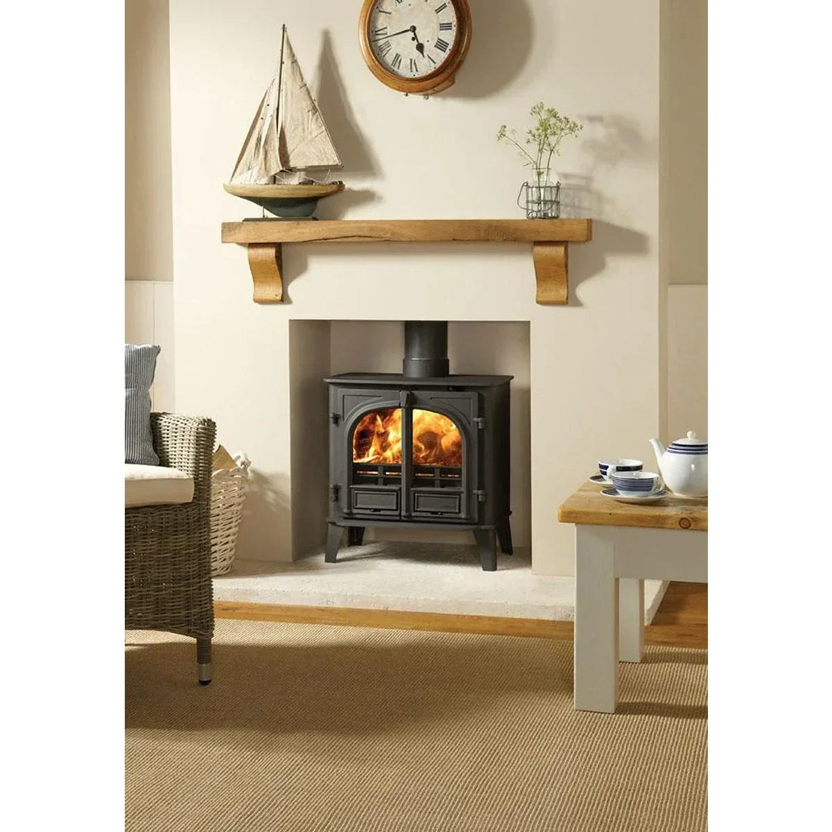 Black wood burning stove with flames in fireplace, mantel shelf, and rustic living room decor