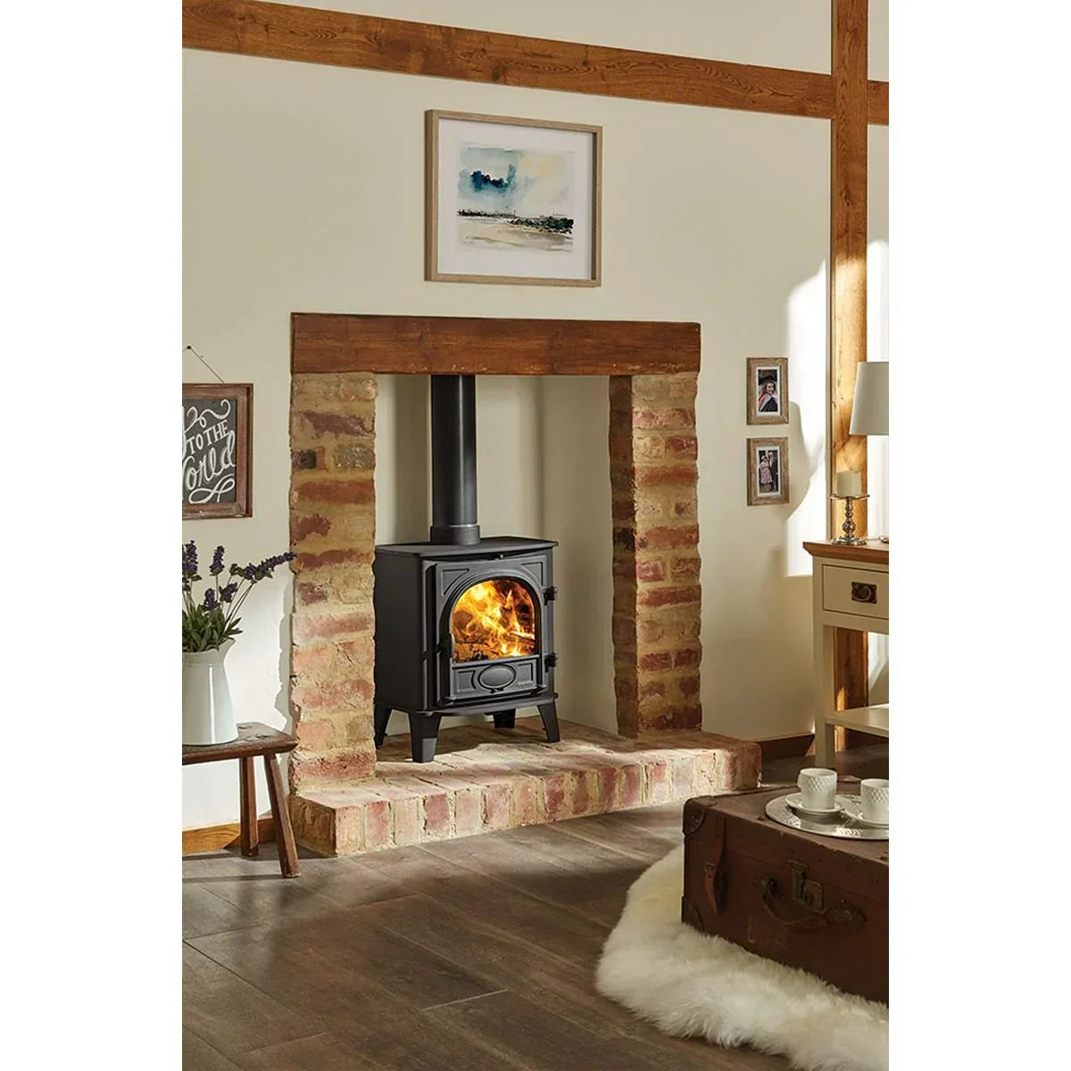 Black wood burning stove with visible flames in a brick fireplace, rustic living room