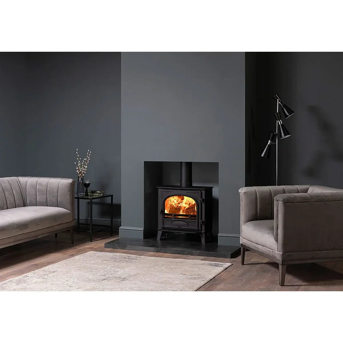 Grey velvet sofas and armchair with wood burning stove in modern living room