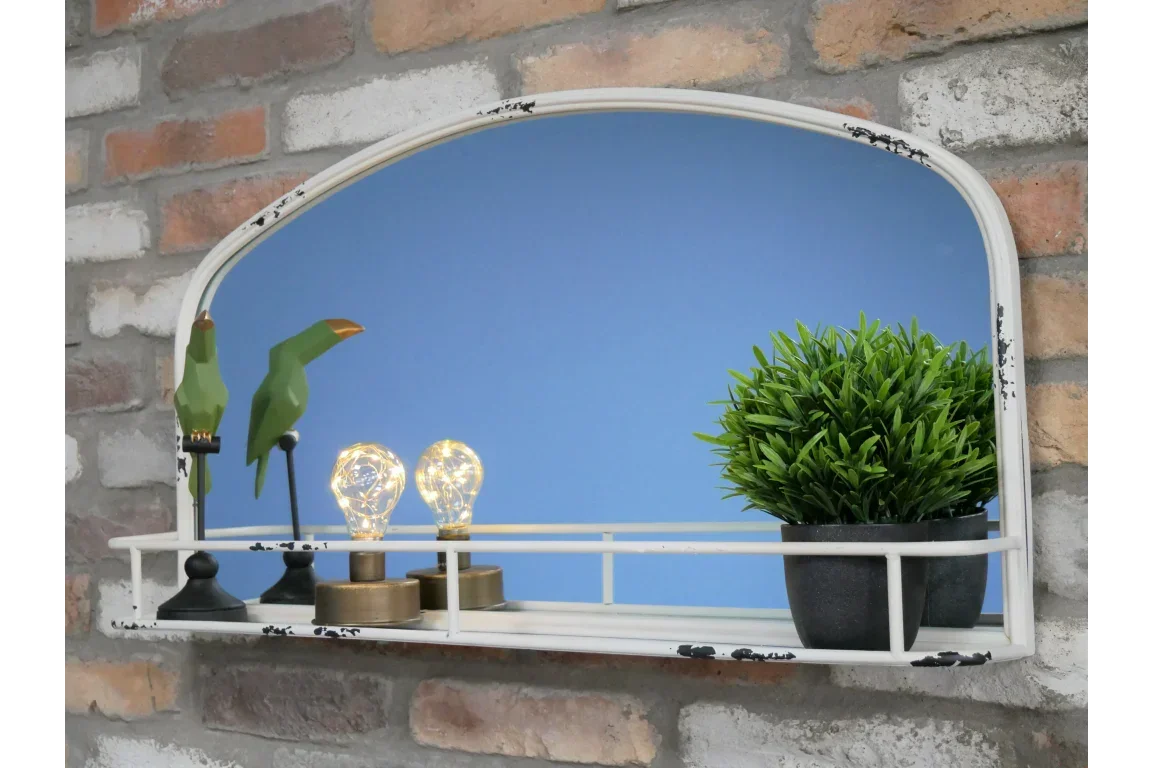Wall mirror with shelf holding green decorative birds, potted plant, and light bulbs