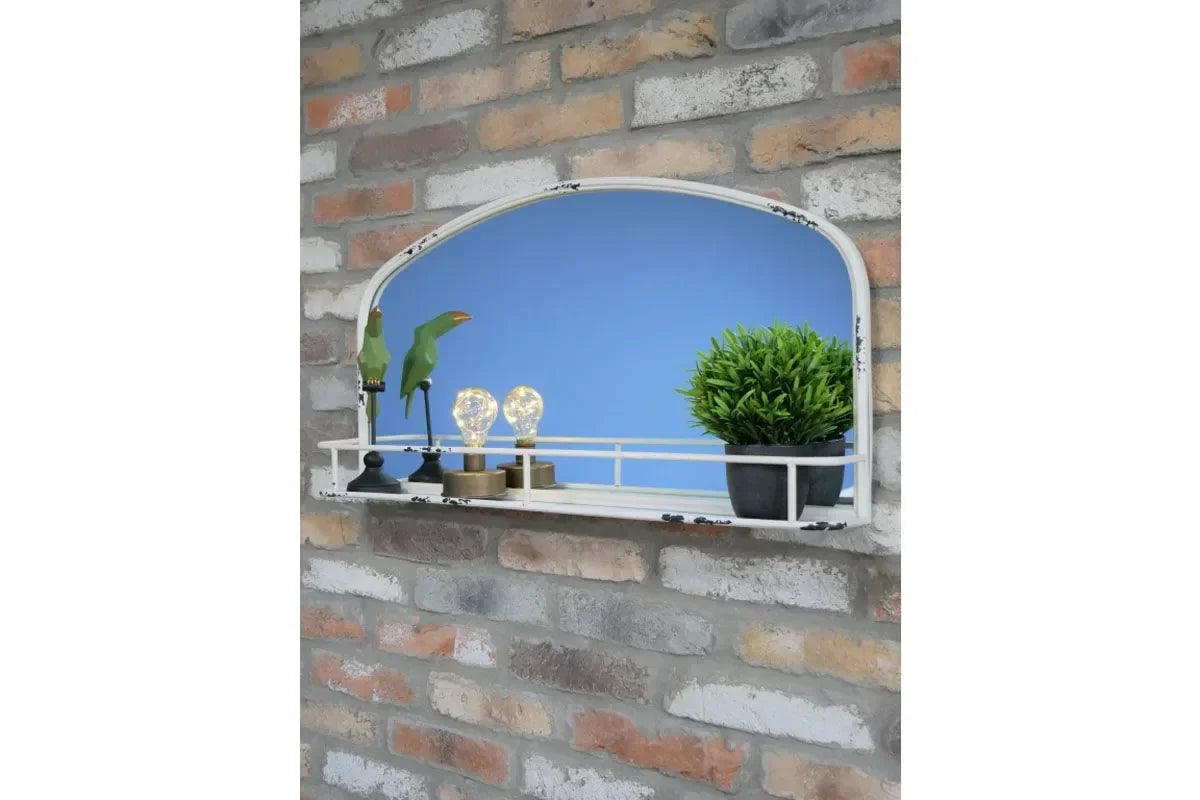 Wall mirror with shelf, potted plant, decorative birds and light bulbs against brick wall