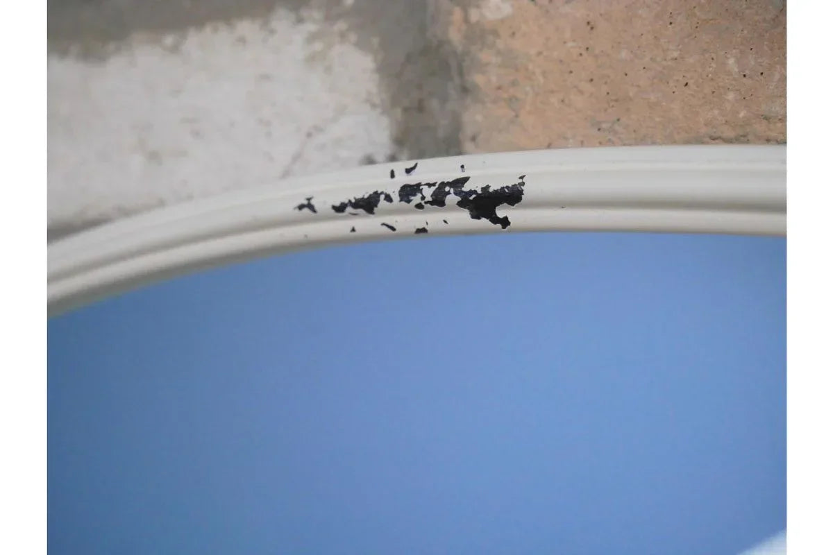 Close up of mirror with chipped white frame and visible paint damage