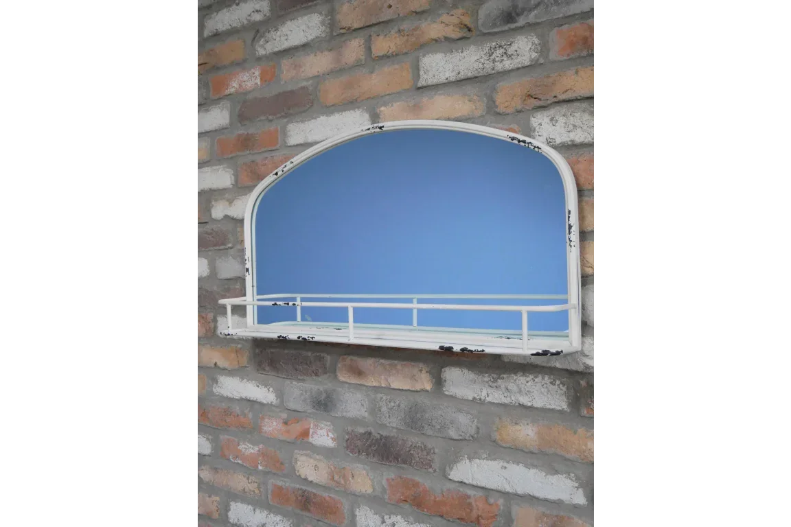 White arched wall mirror with shelf and metal frame mounted on brick wall