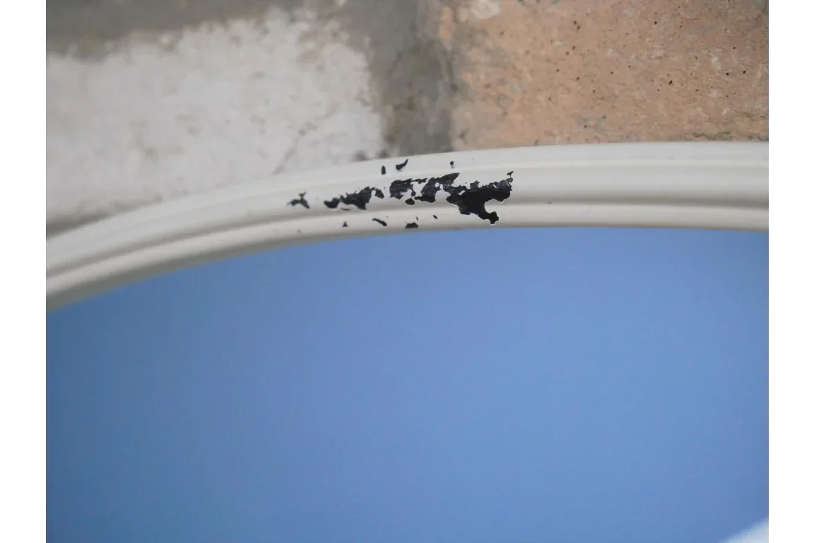 White mirror frame with black paint chips on blue reflective surface