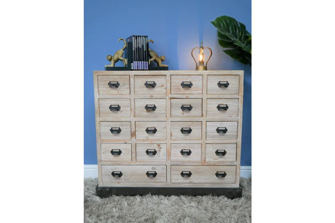 Rustic wooden chest of drawers with black handles against blue wall on shaggy rug
