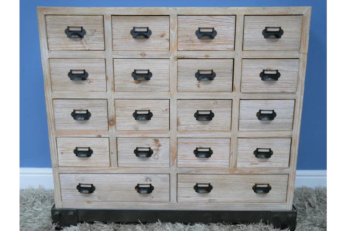Rustic wooden chest of drawers with black metal handles against blue wall
